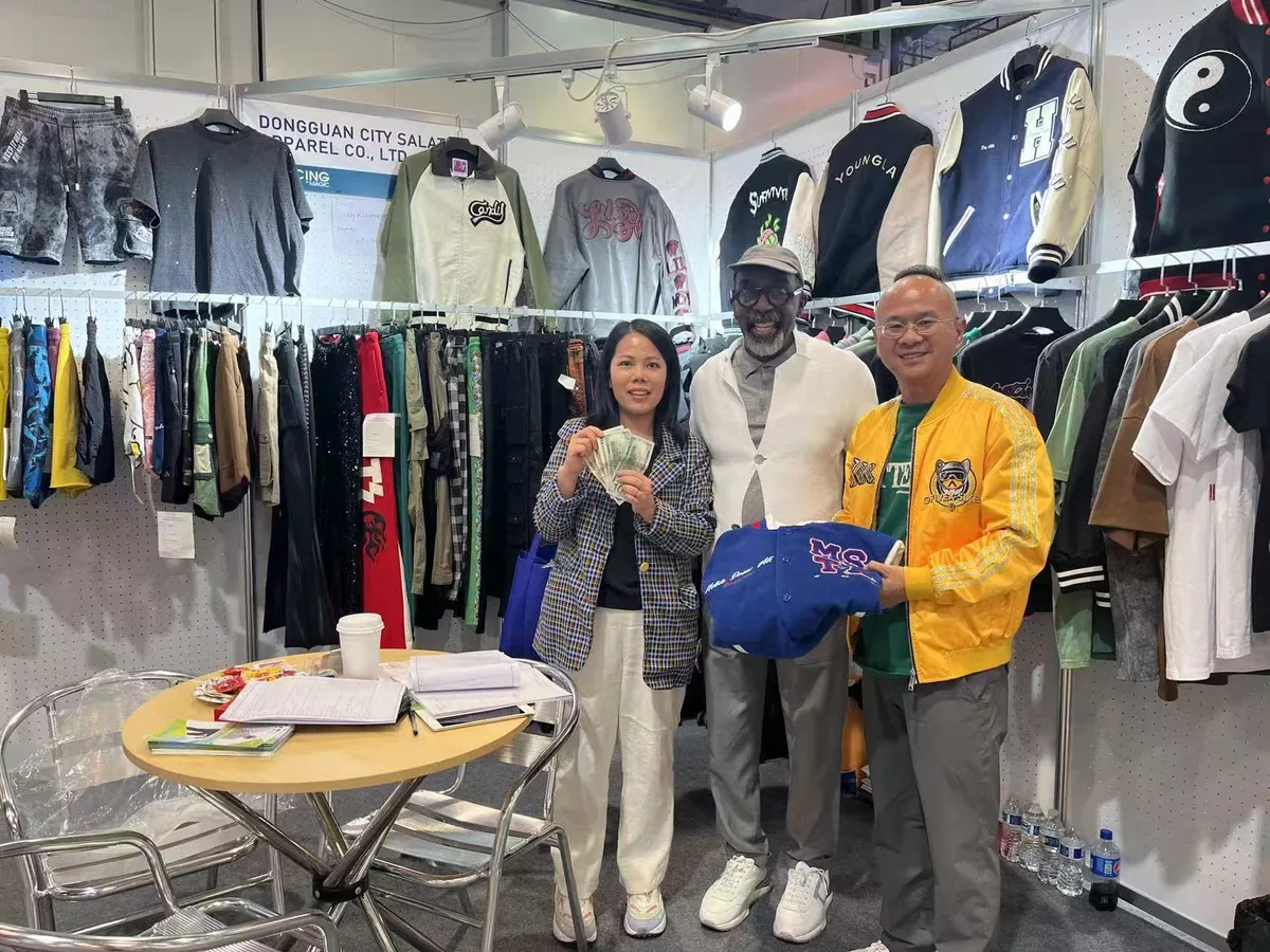 SALATI team and visitors holding a garment at an exhibition booth