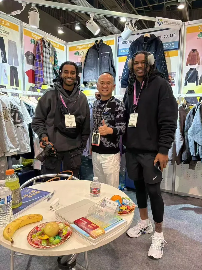 Visitors and a SALATI team member at a booth displaying streetwear samples