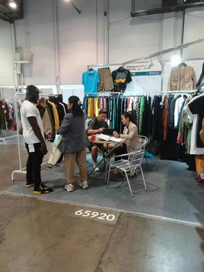 Visitors talking with the SALATI team among displayed garment samples