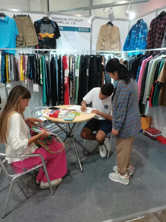 Visitors and SALATI staff seated at a table in the exhibition booth