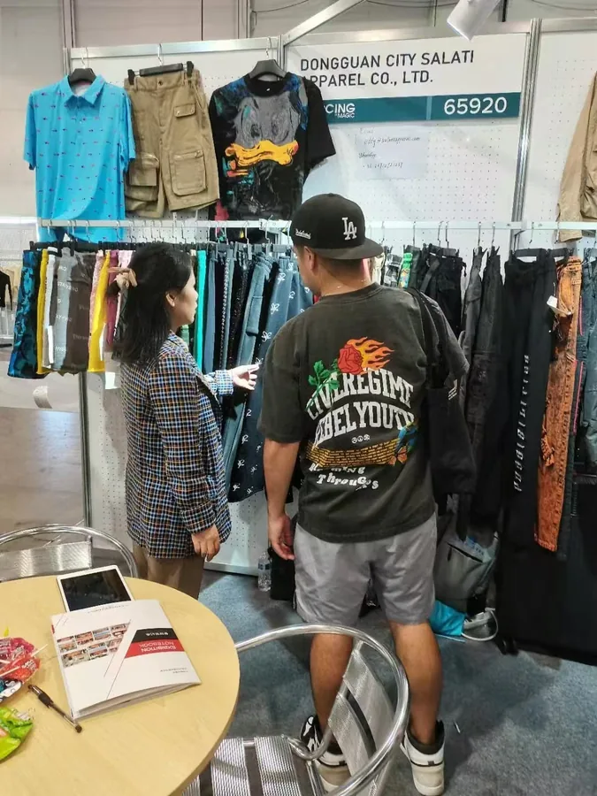 Visitors standing beside the streetwear samples in the SALATI exhibition booth