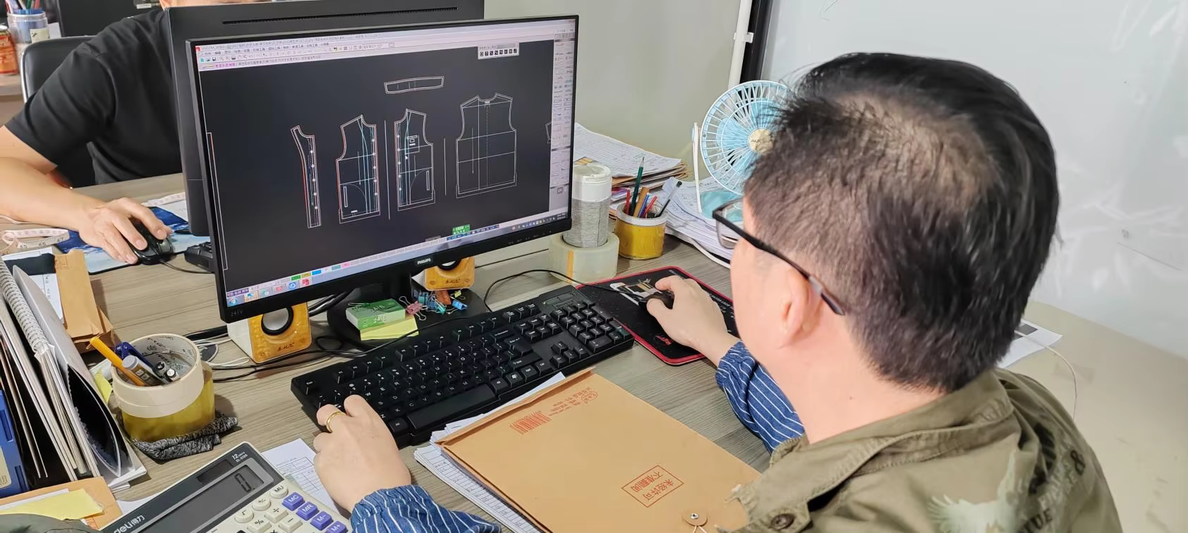 A SALATI pattern maker reviewing digital garment patterns at a CAD workstation