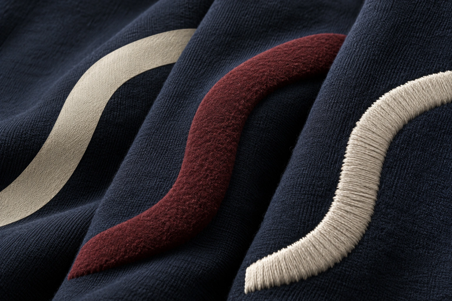 flat ivory print, raised burgundy print and ivory satin stitching on navy cotton